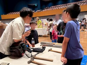 小さな家づくり体験で社長が参加の子供たちに工具説明をする様子