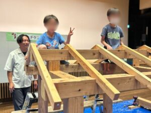 小さな家づくり体験でできあがった家に上って嬉しそうな子どもの様子